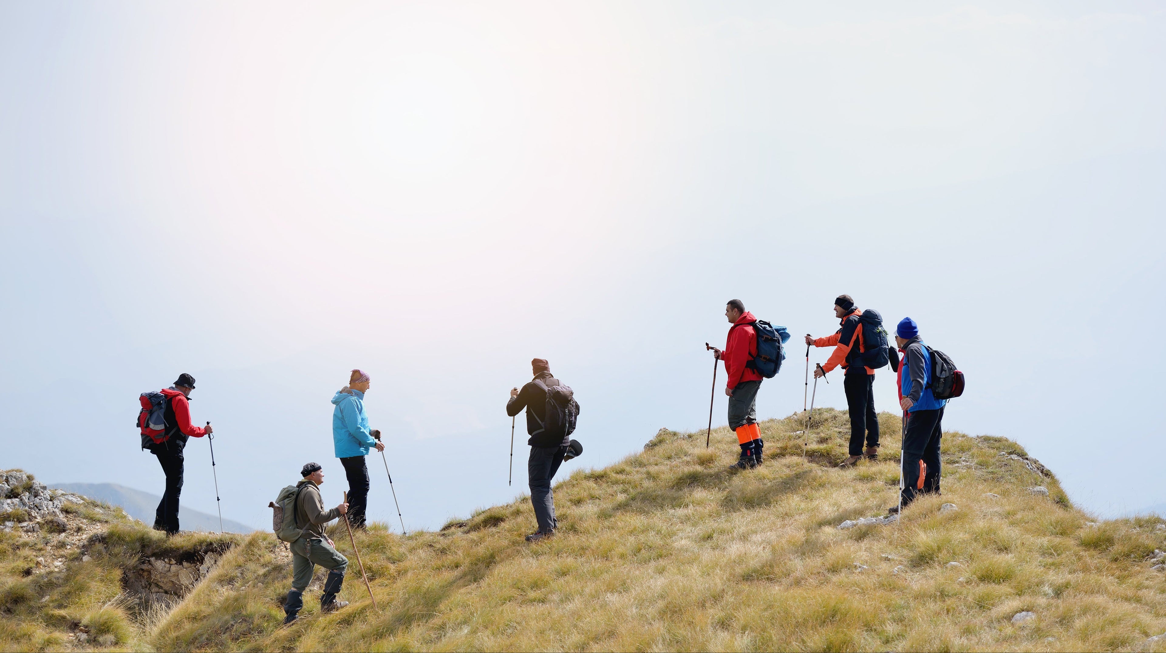 Group of hikers on a mountain trail with backpacks and hiking poles.